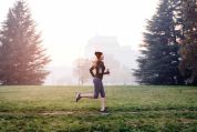 Frau mit Flasche in der Hand joggt früh morgens Frau mit Flasche in der Hand joggt früh morgens